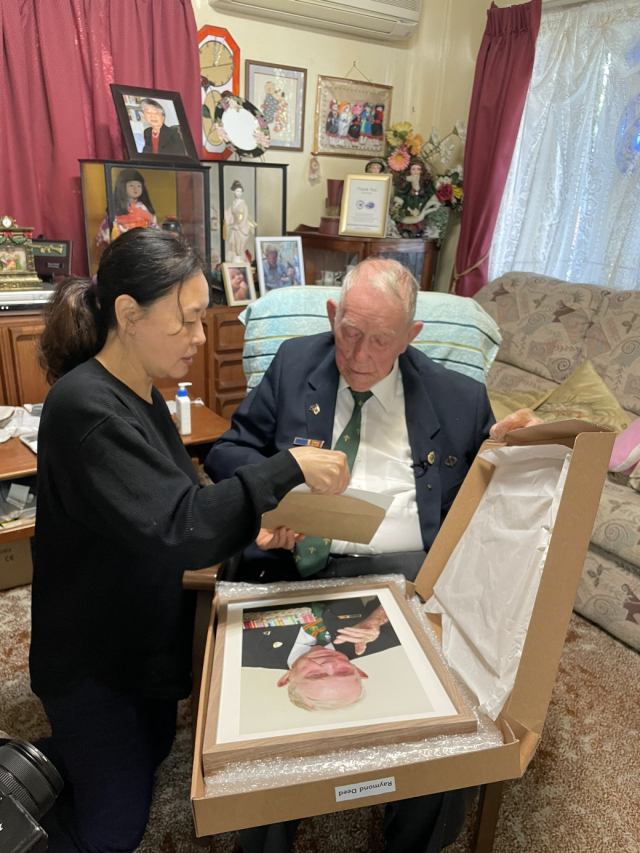 한국전 당시 가평전투에 참전했던 레이먼드 디드씨가 호주 브리즈번의 자택에서 사진을 전달 받고 있다. <사진제공=다큐앤드뉴스코리아>