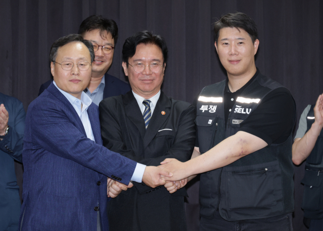 (왼쪽부터) 여명구 삼성전자 DS피플팀장 부사장, 김영훈 고용노동부 장관, 최승호 삼성그룹초기업노동조합 삼성전자지부 위원장이 20일 경기 수원시 경기고용노동청에서 열린 삼성전자 노사 협상에서 ‘2026년 임금 협상 잠정 합의안’에 서명한 후 손을 맞잡고 있다. <사진=연합뉴스>